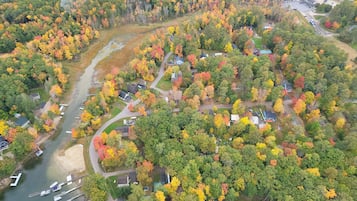 An aerial view of a residential area with houses, a river, and a dock with boats.