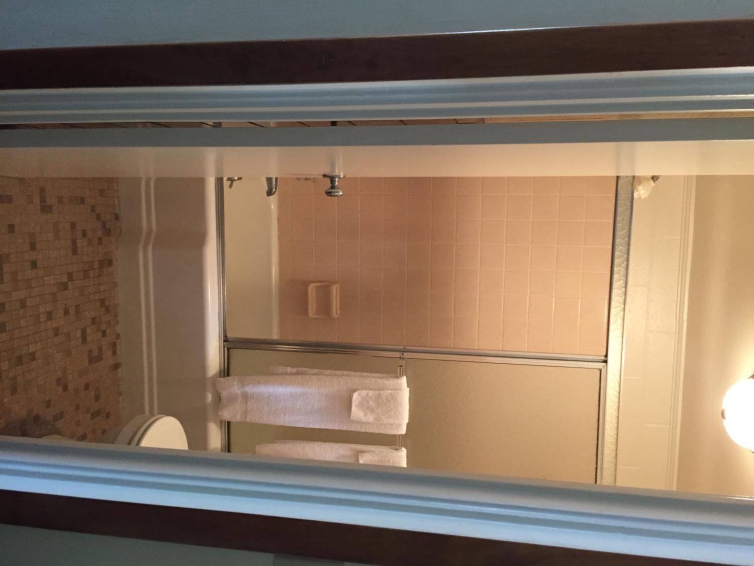 A bathroom with a glass shower enclosure, a tiled wall, and a towel rack.