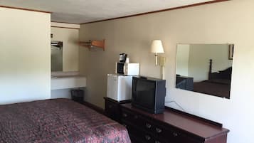 A hotel room with a bed, a dresser, a television, a lamp, and a mirror.