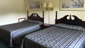 Habitación de hotel con dos camas individuales, una mesita de noche, una lámpara y dos obras de arte enmarcadas en las paredes.