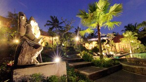 Una statua in un giardino con palme e una piscina.