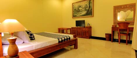 A hotel room with a bed, a television, a wooden cabinet, a chair, and a painting on the wall.