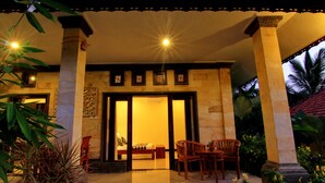 L'ingresso di un hotel con un portico coperto, un letto e un'area salotto con sedie.