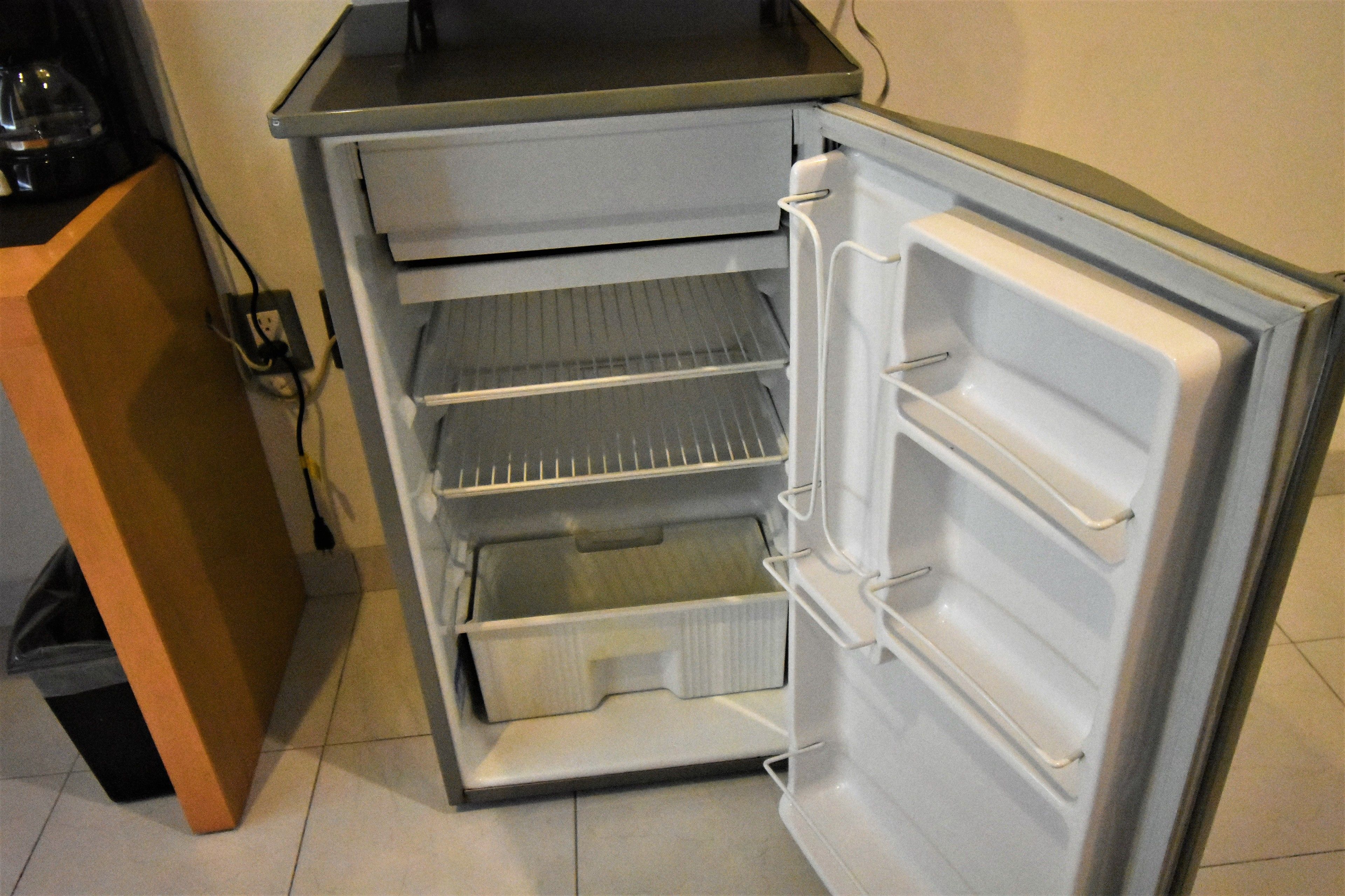 Un refrigerador abierto con varias repisas y un compartimento congelador.