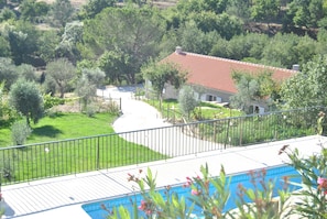 Une propriété résidentielle dotée d’une piscine, d’une maison à toit rouge et d’un jardin bien entretenu.
