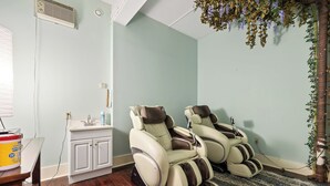 A room with two massage chairs, a small white cabinet, and a wooden table with a container. - Suites at The Red Rock Vacation rentals (Hot Springs)
