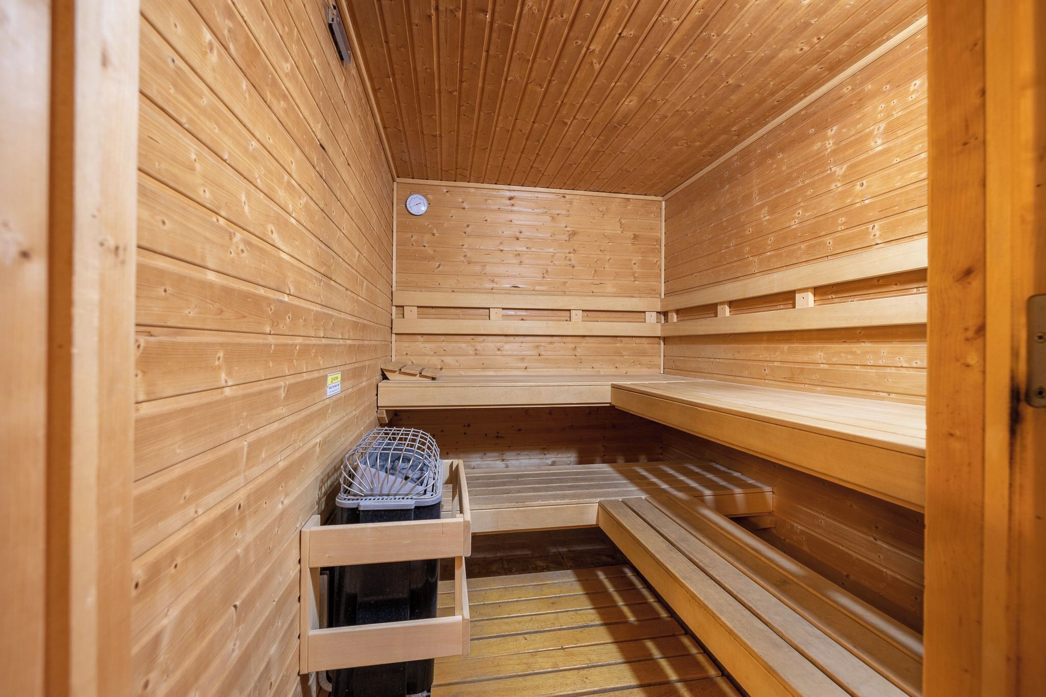 Una sauna con paredes y bancos de madera, un reloj y un perchero para toallas.