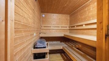 Una sauna con paredes y bancos de madera, un reloj y un perchero para toallas.
