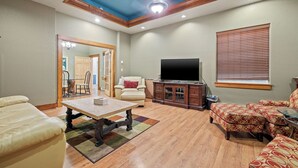 A living room with a wooden ceiling, a television, a sofa, and a dining table. - Suites at The Red Rock Vacation rentals (Hot Springs)