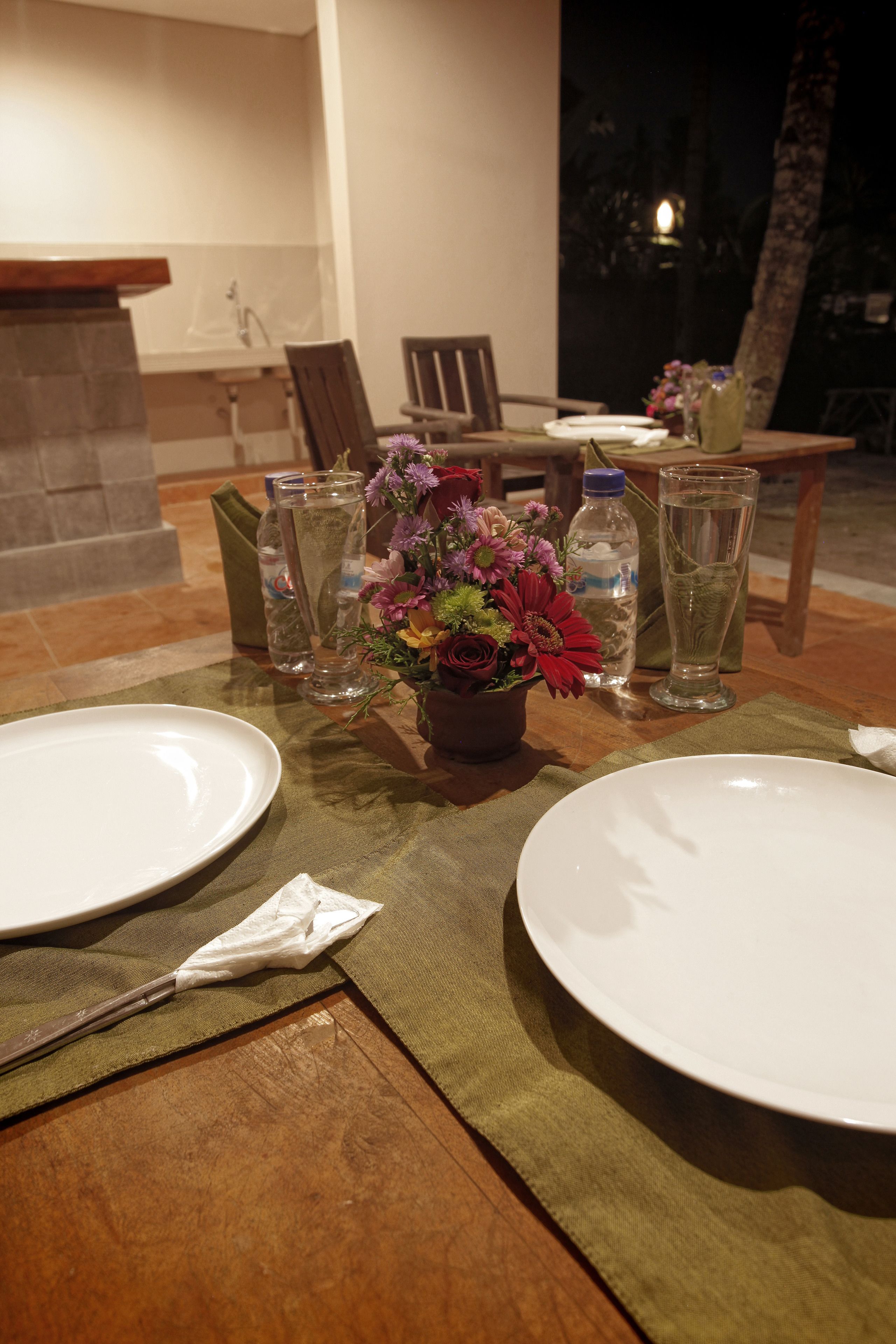 A table set for two with a vase of flowers, two water bottles, and a glass of water.