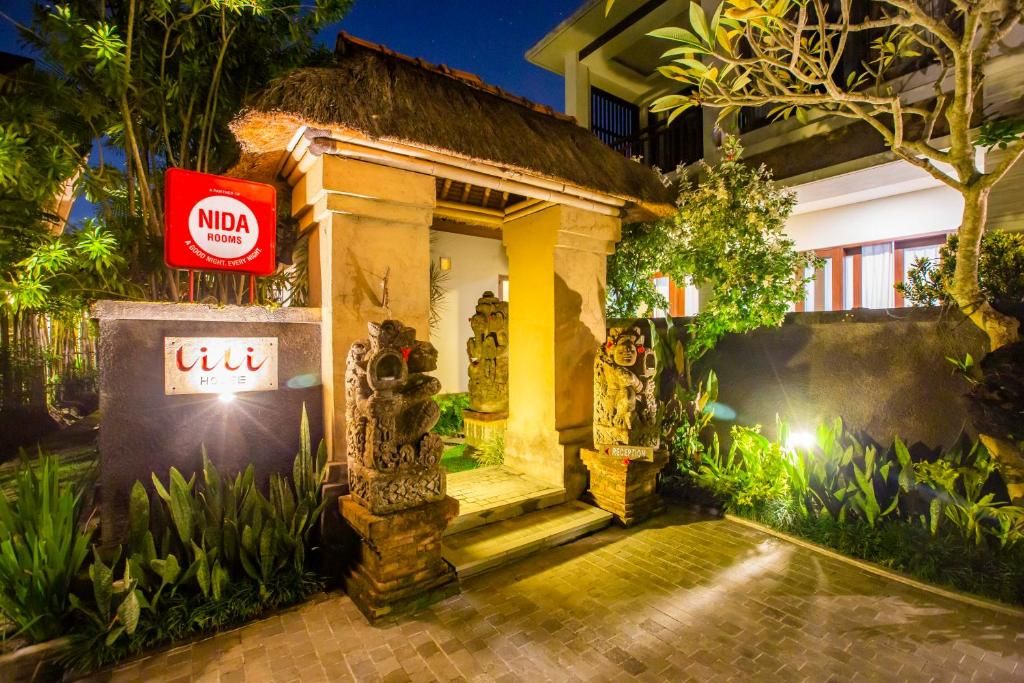 A reception area with a thatched roof, a signboard, and stone sculptures.