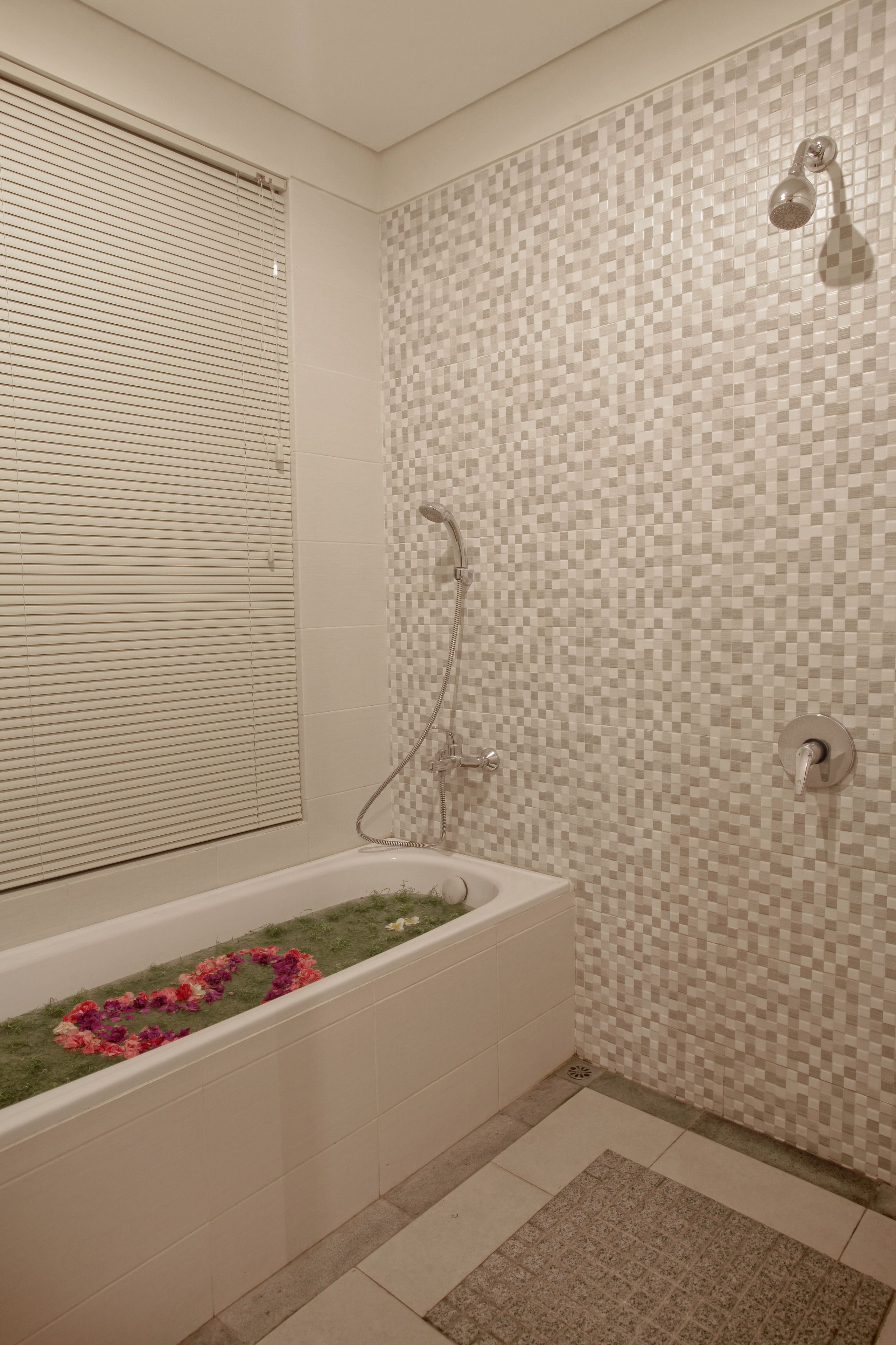 A bathroom with a bathtub, shower, and tiled walls.
