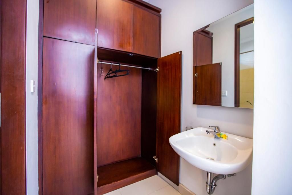 Un baño con un armario de madera, un lavamanos blanco y un espejo.