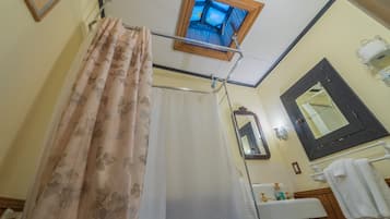 Un baño con cortina de ducha, una ventana, un espejo y un lavabo.