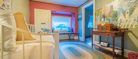 A room with a bed, a desk, a chair, a window, and a painting on the wall.