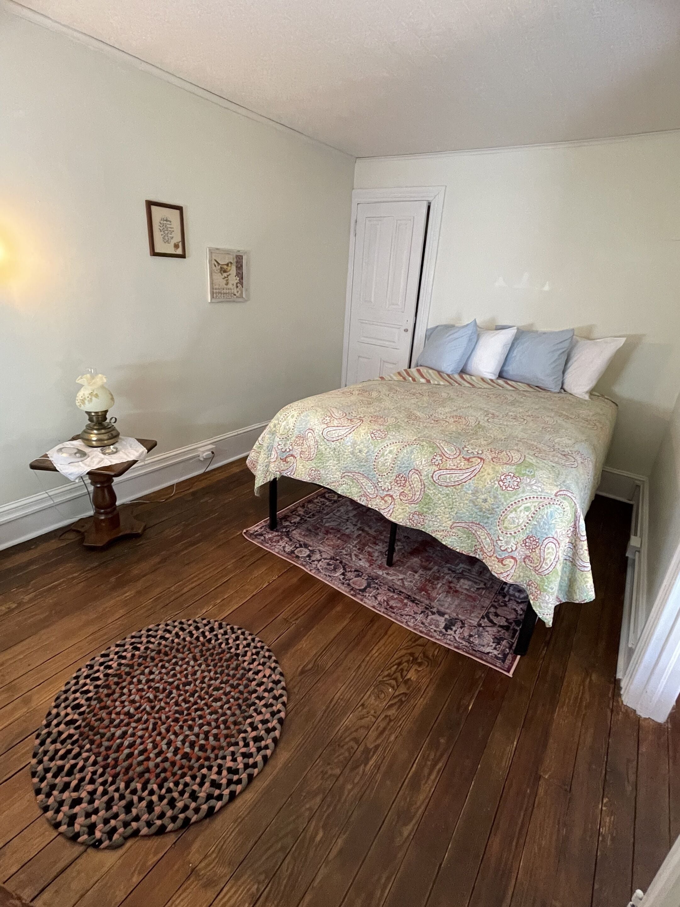 A bedroom with a bed, a nightstand, a lamp, and a rug.