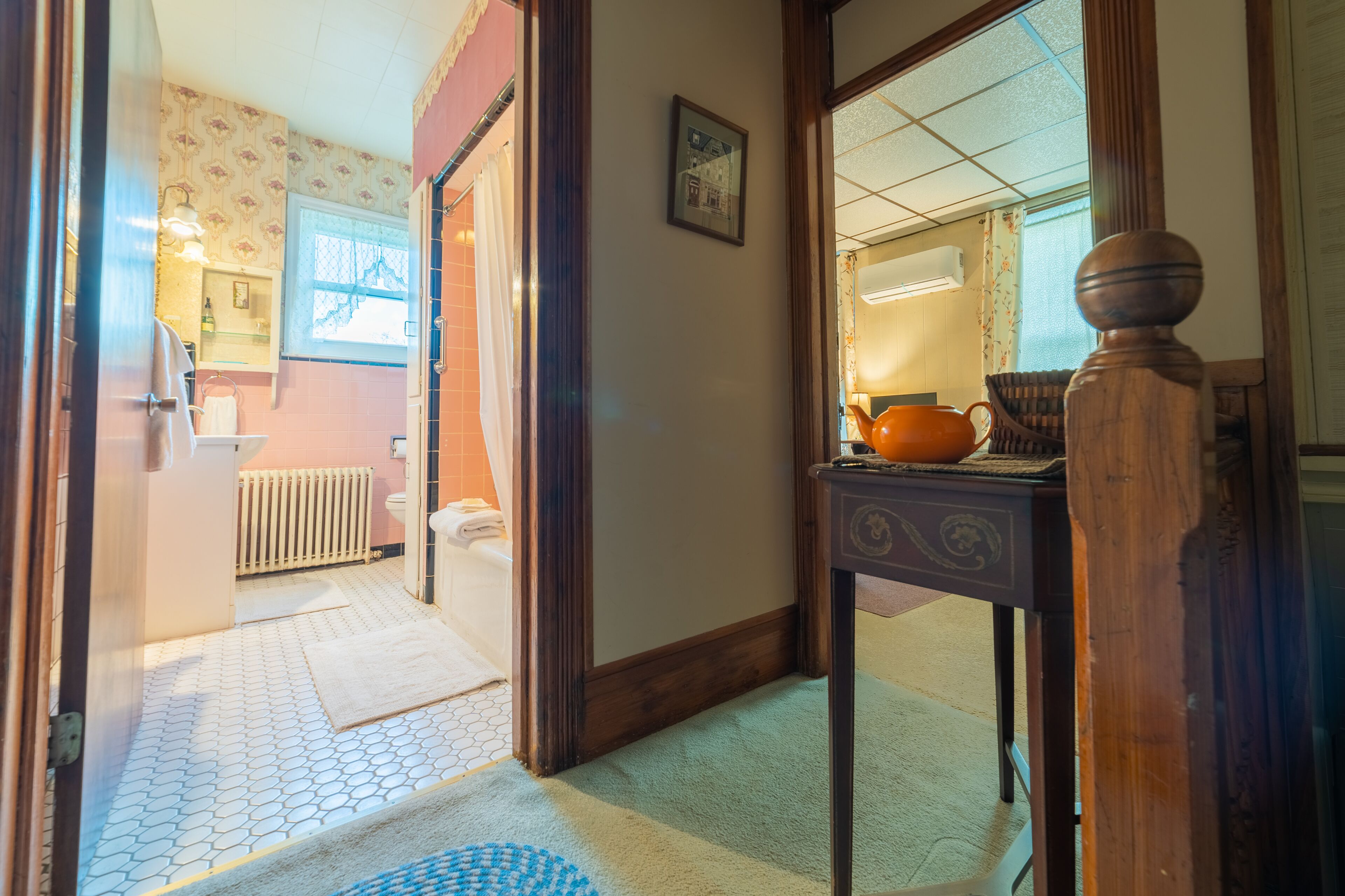 A hallway with a tiled floor, a wooden door, a radiator, and a table with a teapot.