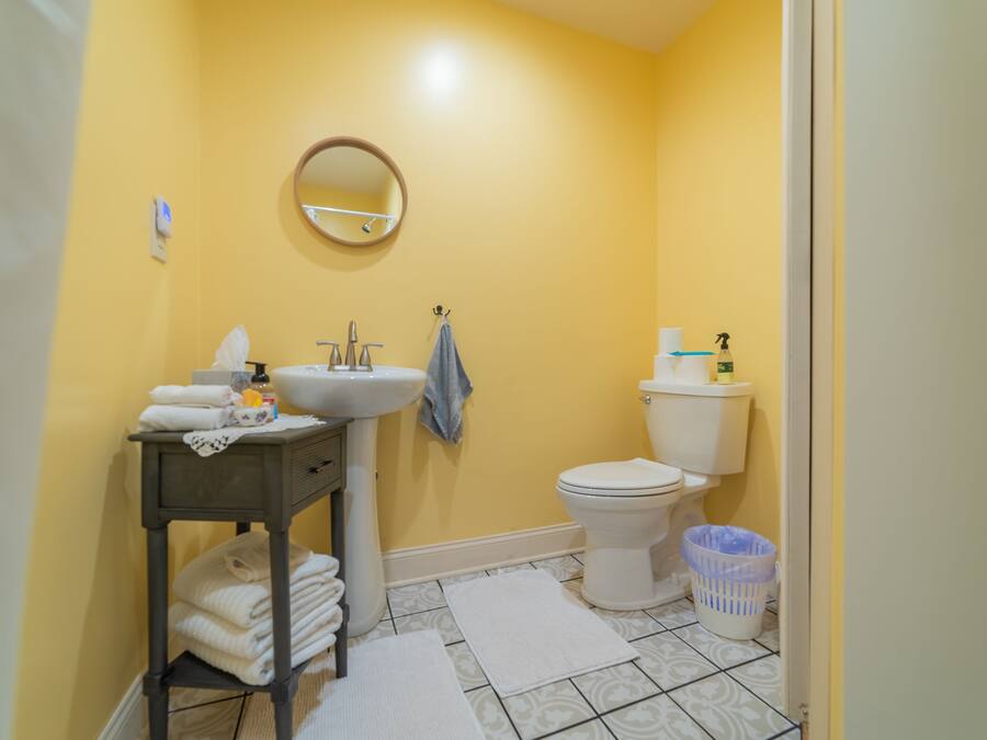A bathroom with a sink, mirror, toilet, and a small table with towels.