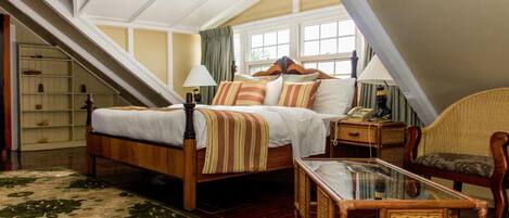 A bedroom with a wooden bed, a glass table, and a wicker chair.