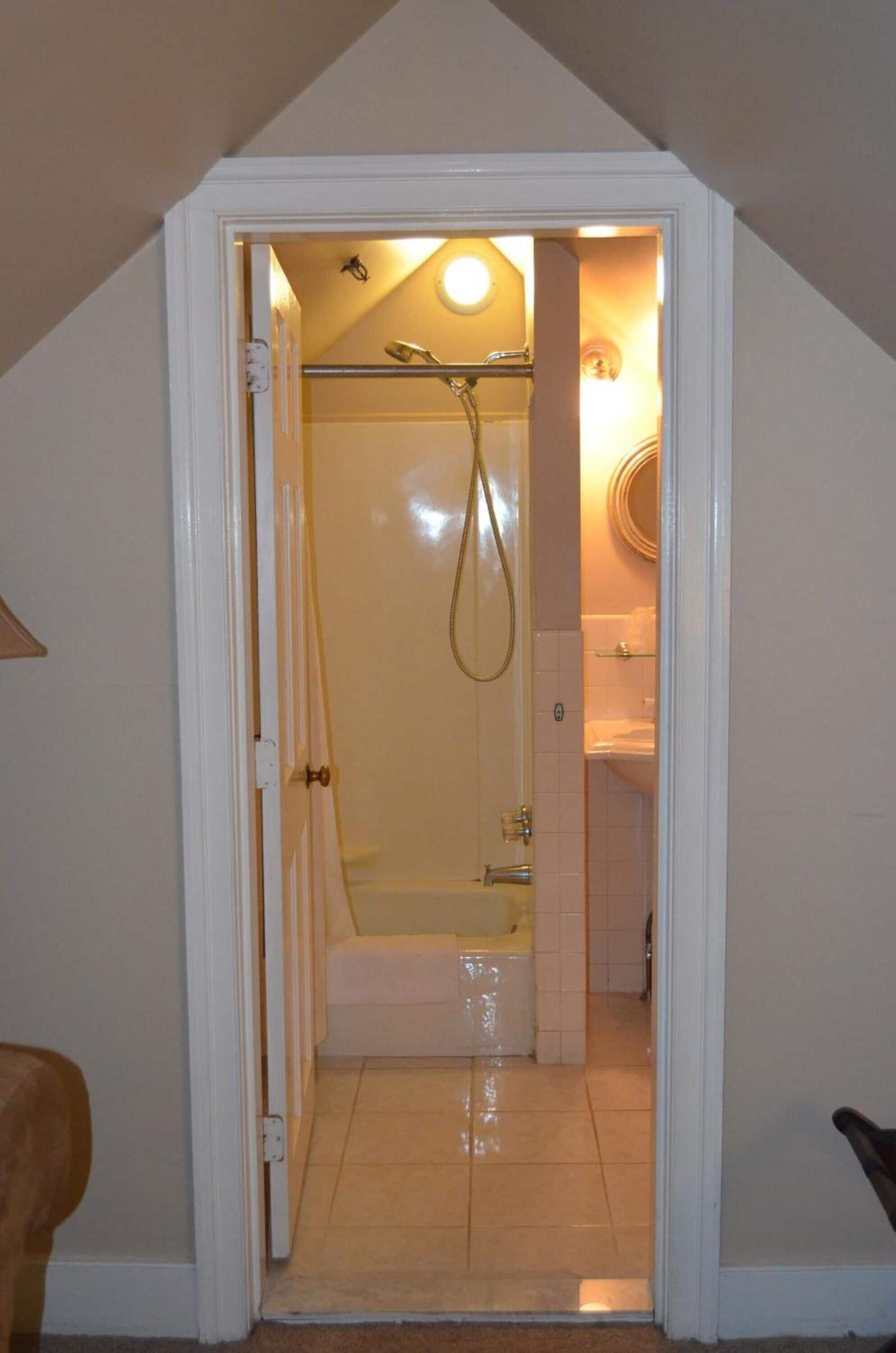 A small, narrow bathroom with a shower, a toilet, and a sink.
