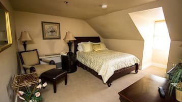A bedroom with a bed, bedside lamps, a chair, a small table, and a decorative plant.
