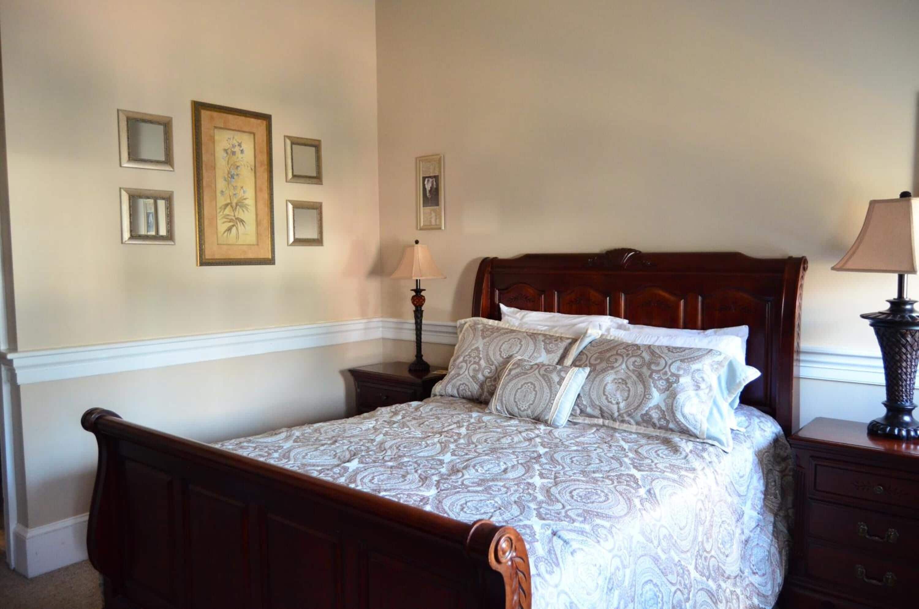 A neatly made bed with a patterned bedspread, a wooden headboard, and a nightstand with a lamp.