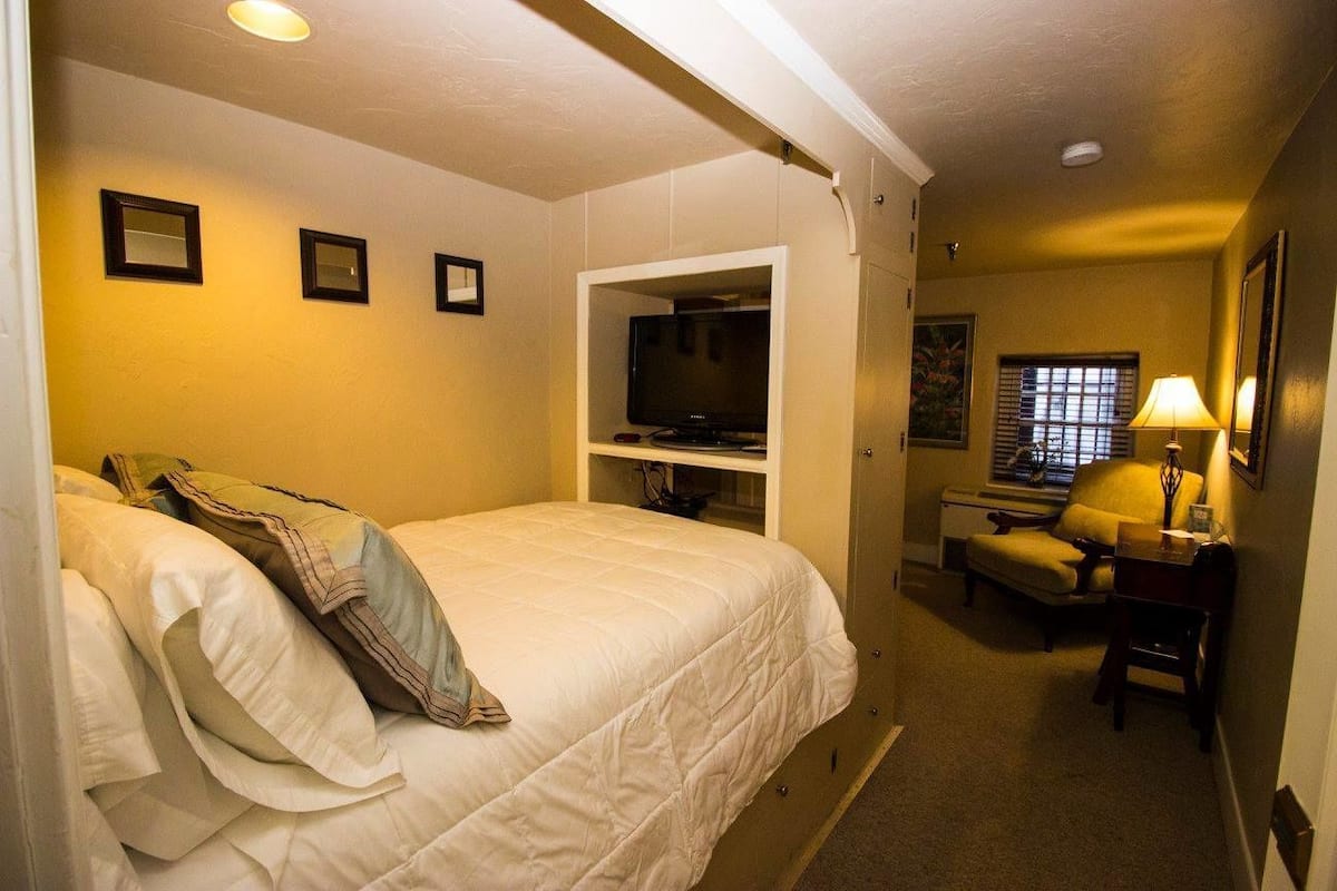 A hotel room with a bed, a television, a desk, and a chair.
