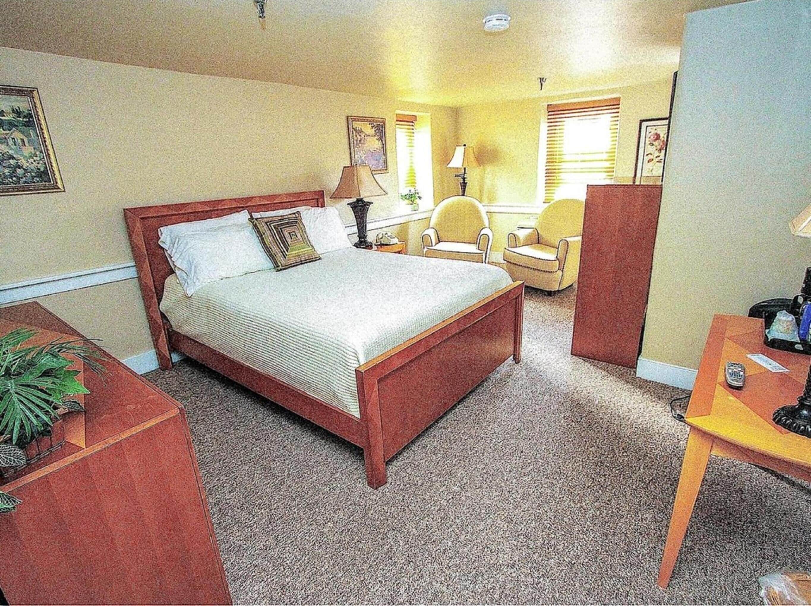 Una habitación de hotel con una cama grande, un escritorio, una silla y una pequeña mesa.