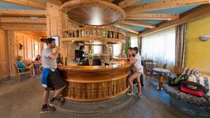Un interior de madera con una barra central, zonas de estar y un techo decorativo.