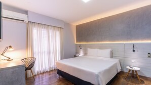 Een moderne hotelkamer met een groot bed, nachtkastjes, een bureau met lamp en een stoel.