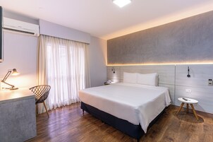 Una camera d'albergo moderna con un grande letto, comodini, una scrivania con una lampada e una sedia.