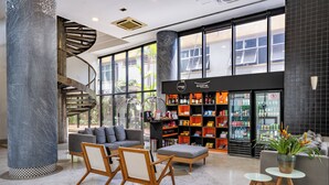 Een moderne lobby met een spiltrap, een zithoek en een bar met drankenkasten.