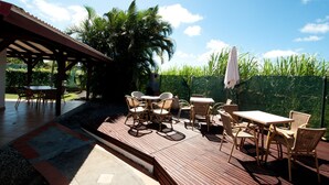 An outdoor patio with wooden flooring, wicker furniture, and a covered seating area. - Jéricho Gîtes & Spa (Capesterre-de-Marie-Galante)