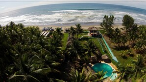 A resort with a pool, palm trees, and a beach view. - Azul Surf Club (El Cuco)