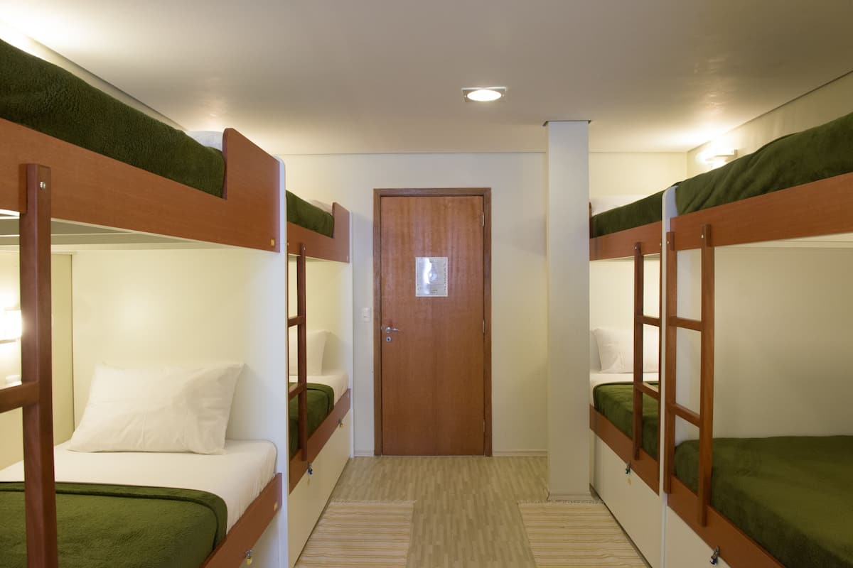A room with bunk beds, a wooden door, and a light switch on the wall.
