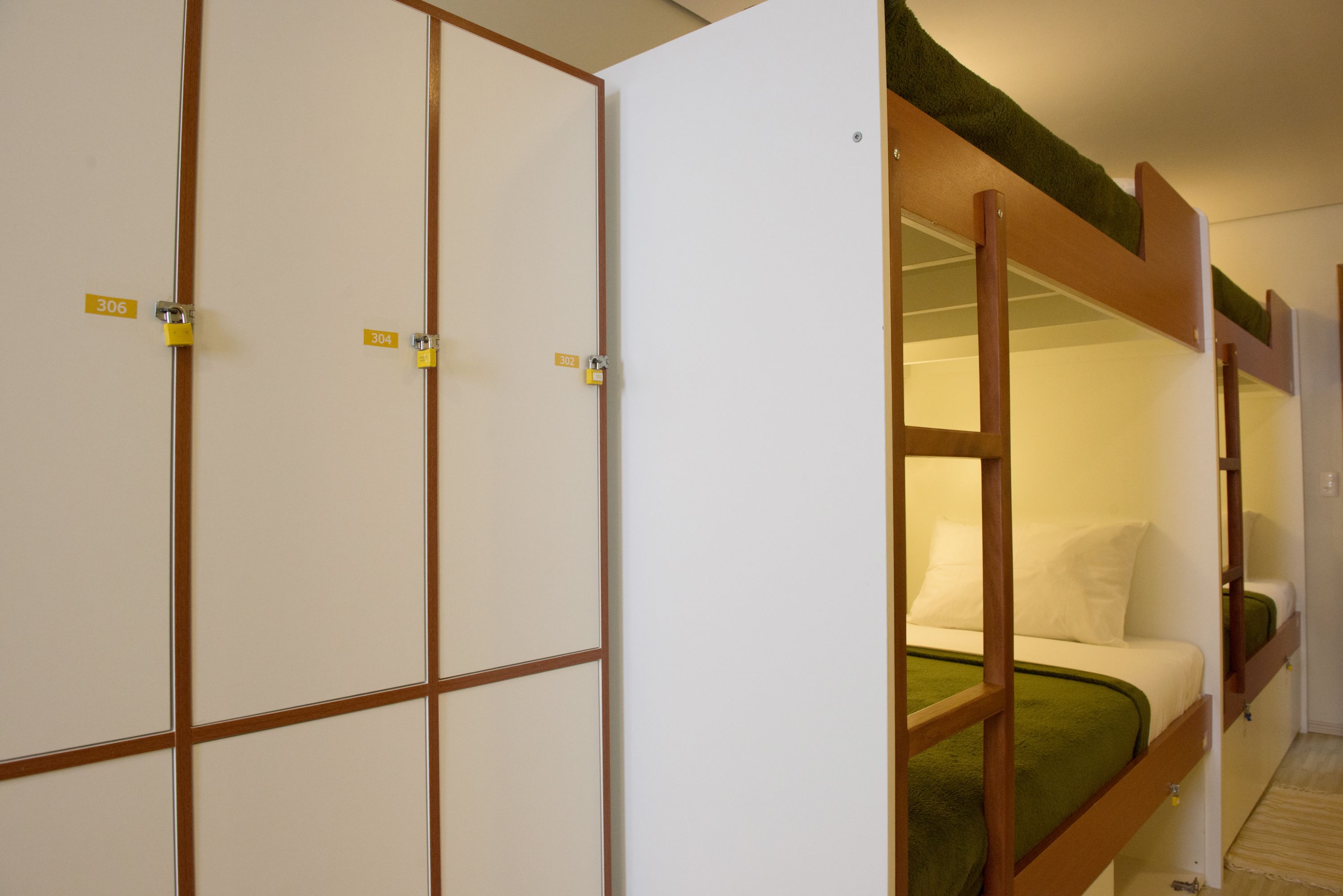 A room with a bunk bed, a wardrobe with multiple compartments, and a door with a lock.