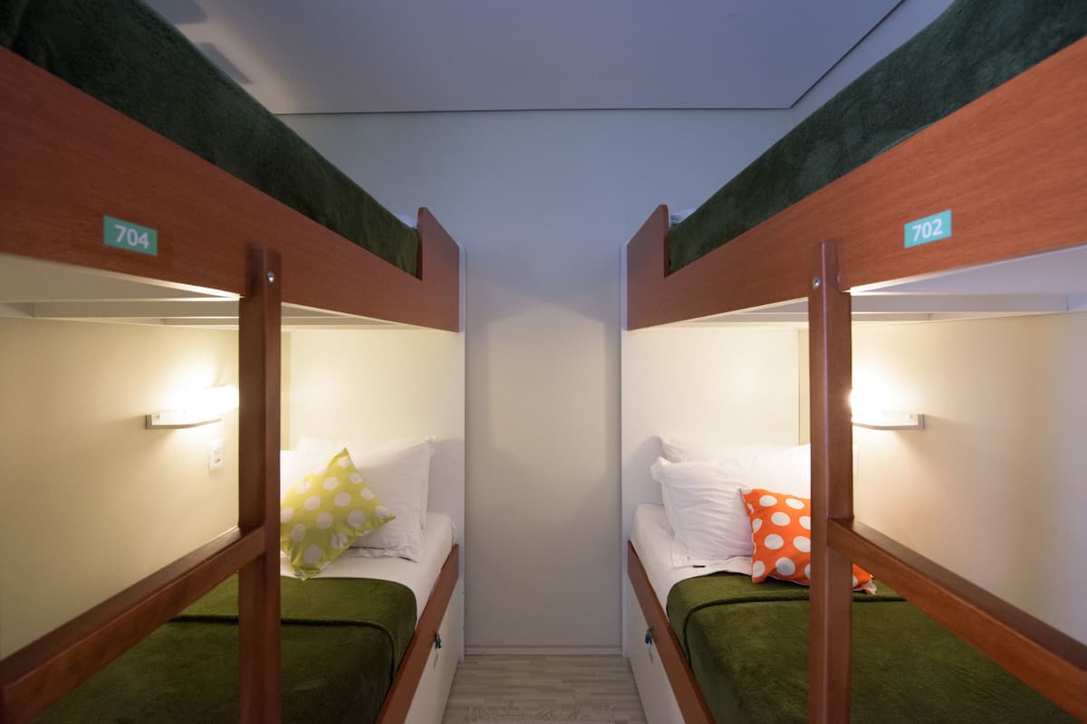 Two bunk beds with numbers 704 and 702, each with a pillow and a small bedside table.