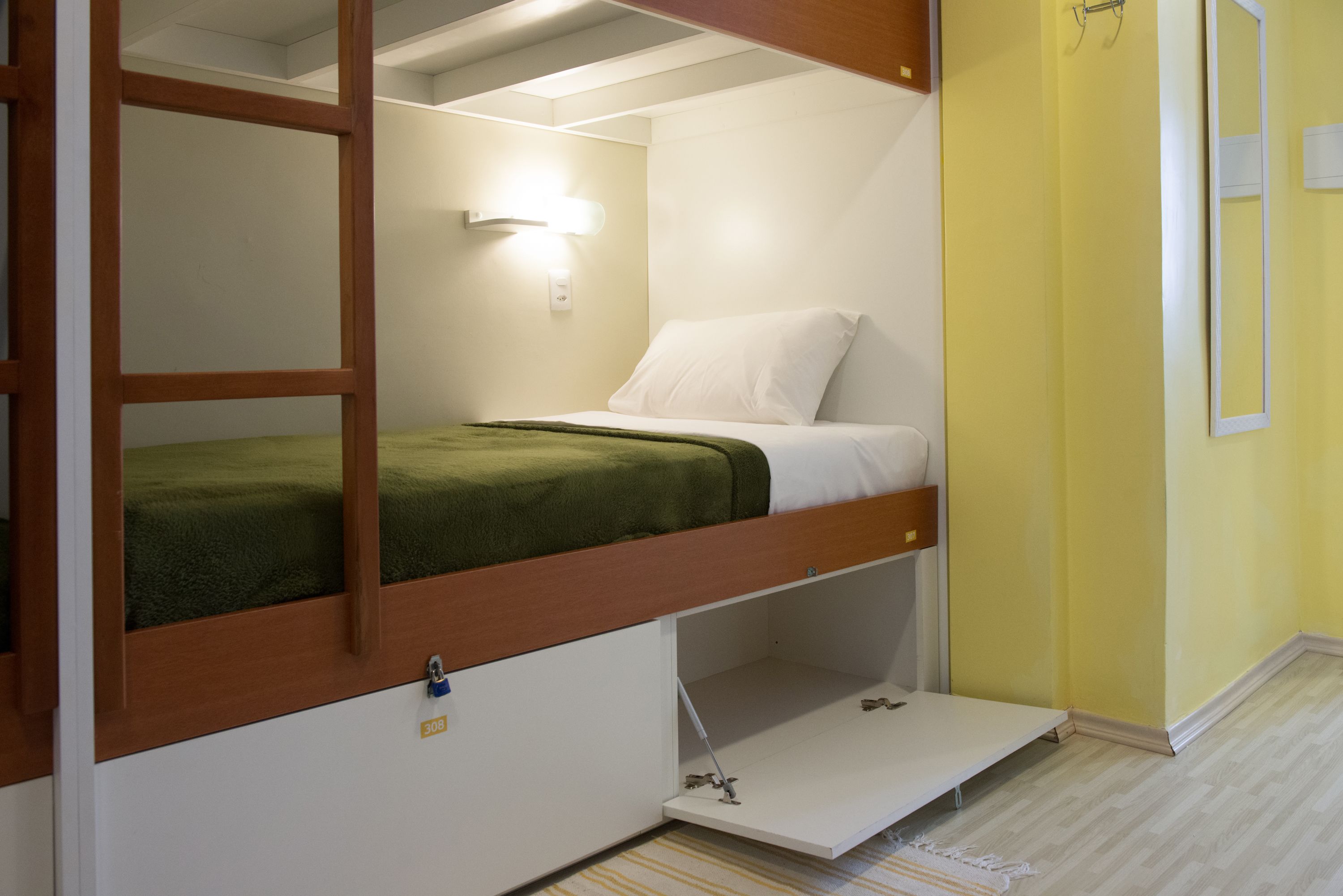 A bunk bed with a pull-out desk, a bedside lamp, and a small shelf.