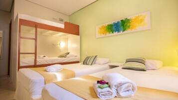 A hotel room with two single beds, a bunk bed, and a colorful abstract painting on the wall.