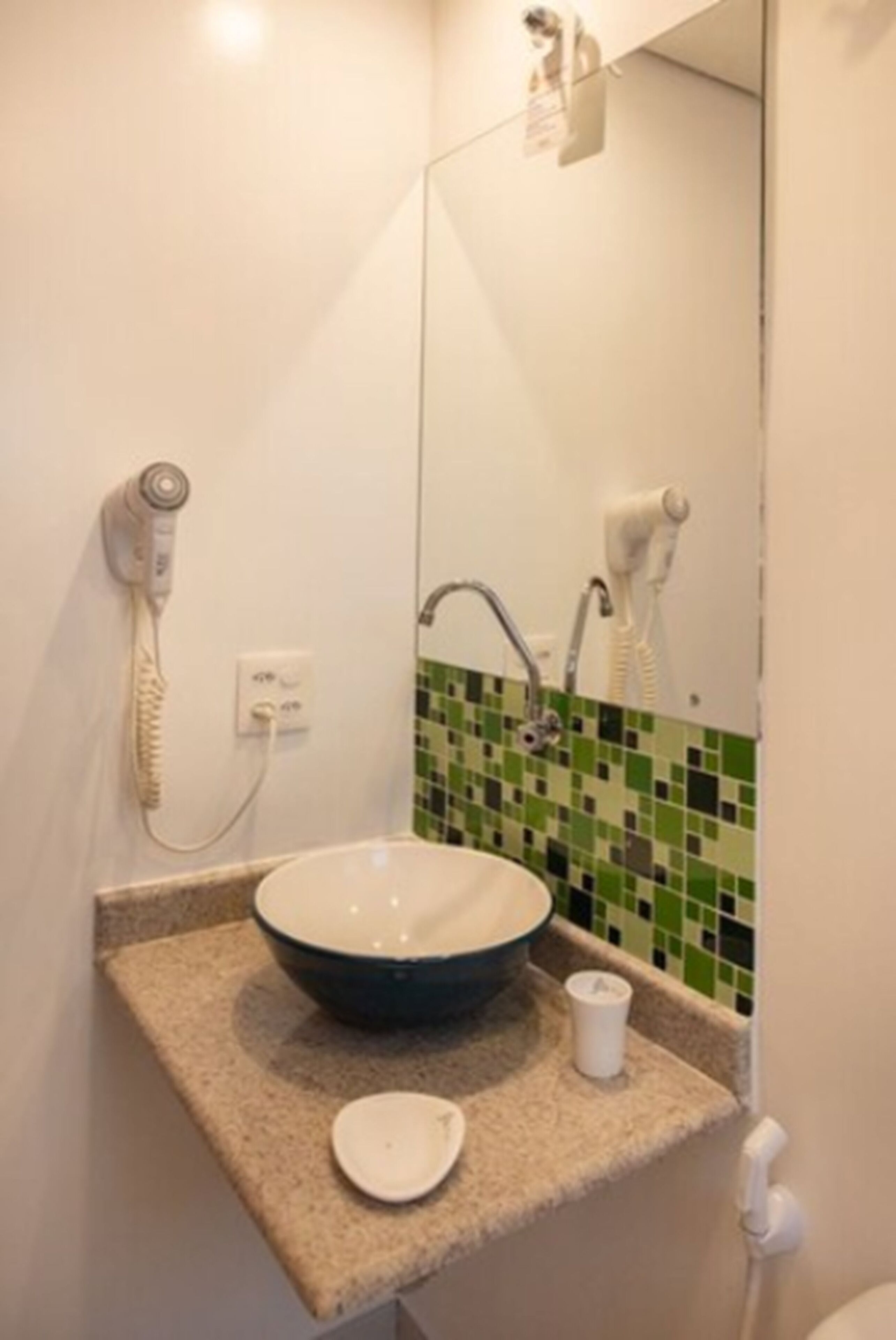A bathroom with a sink, a hairdryer, and a mirror.