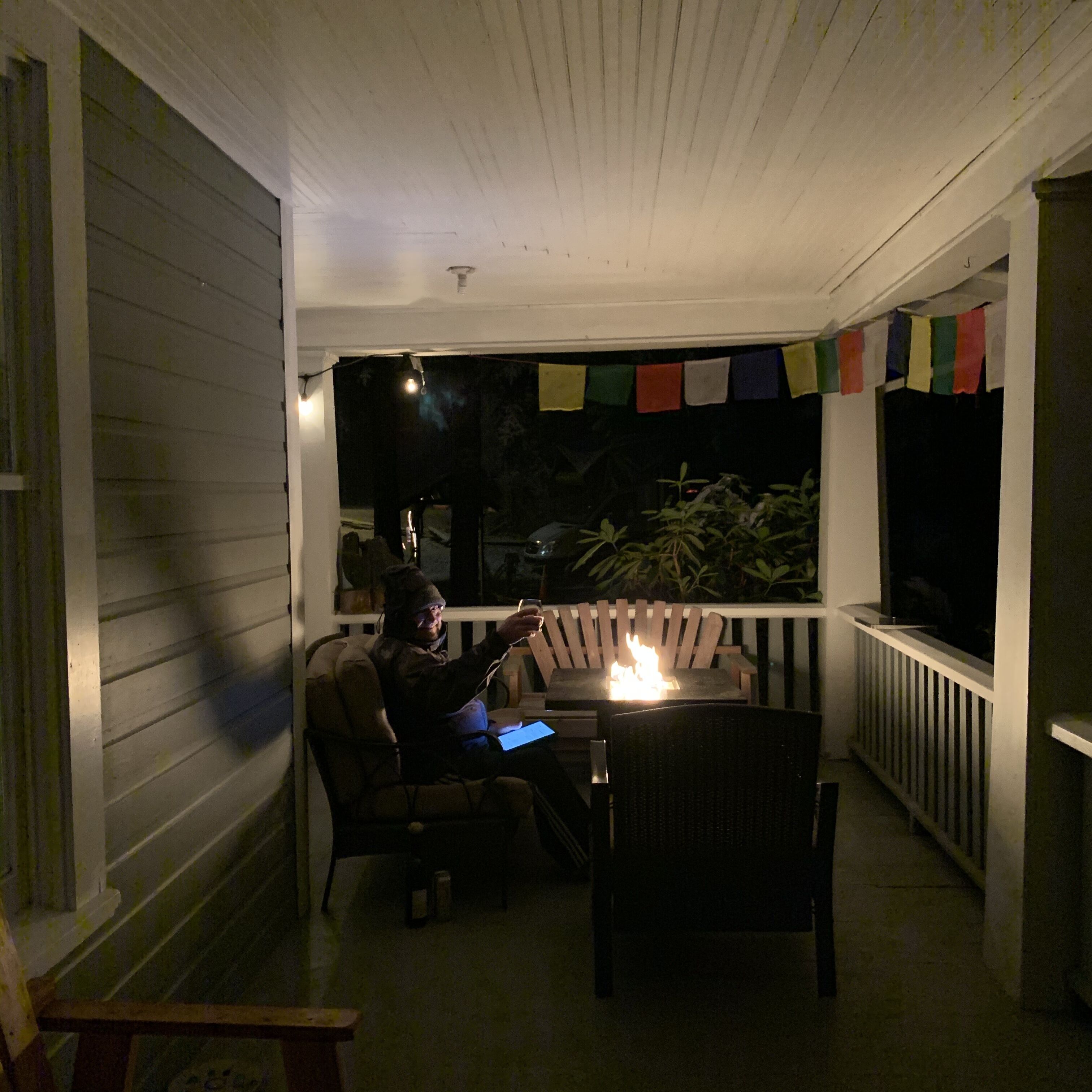 Un porche techado con una chimenea, asientos y una pantalla de televisión.