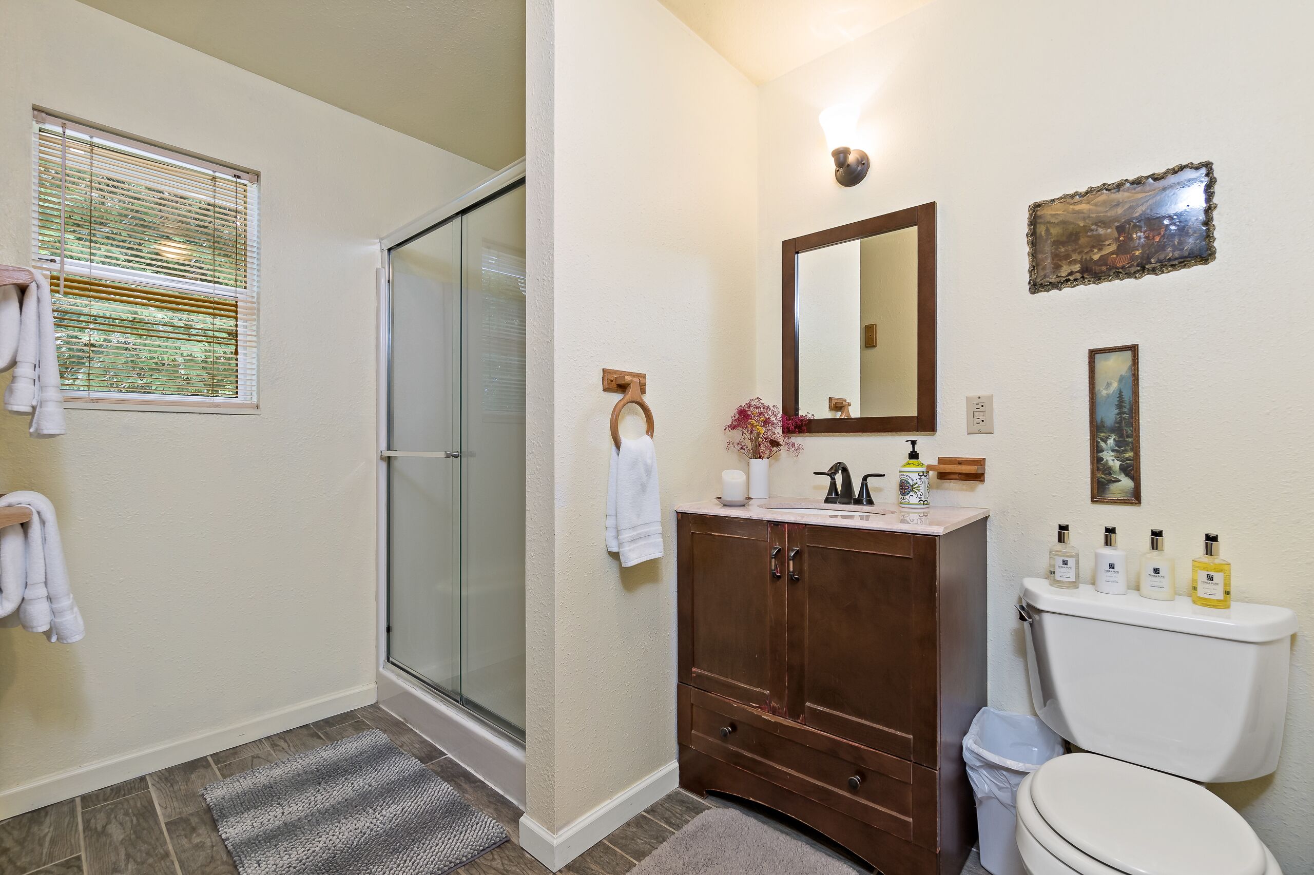 Une salle de bain avec une douche en verre, un meuble-lavabo en bois, des toilettes et un miroir.