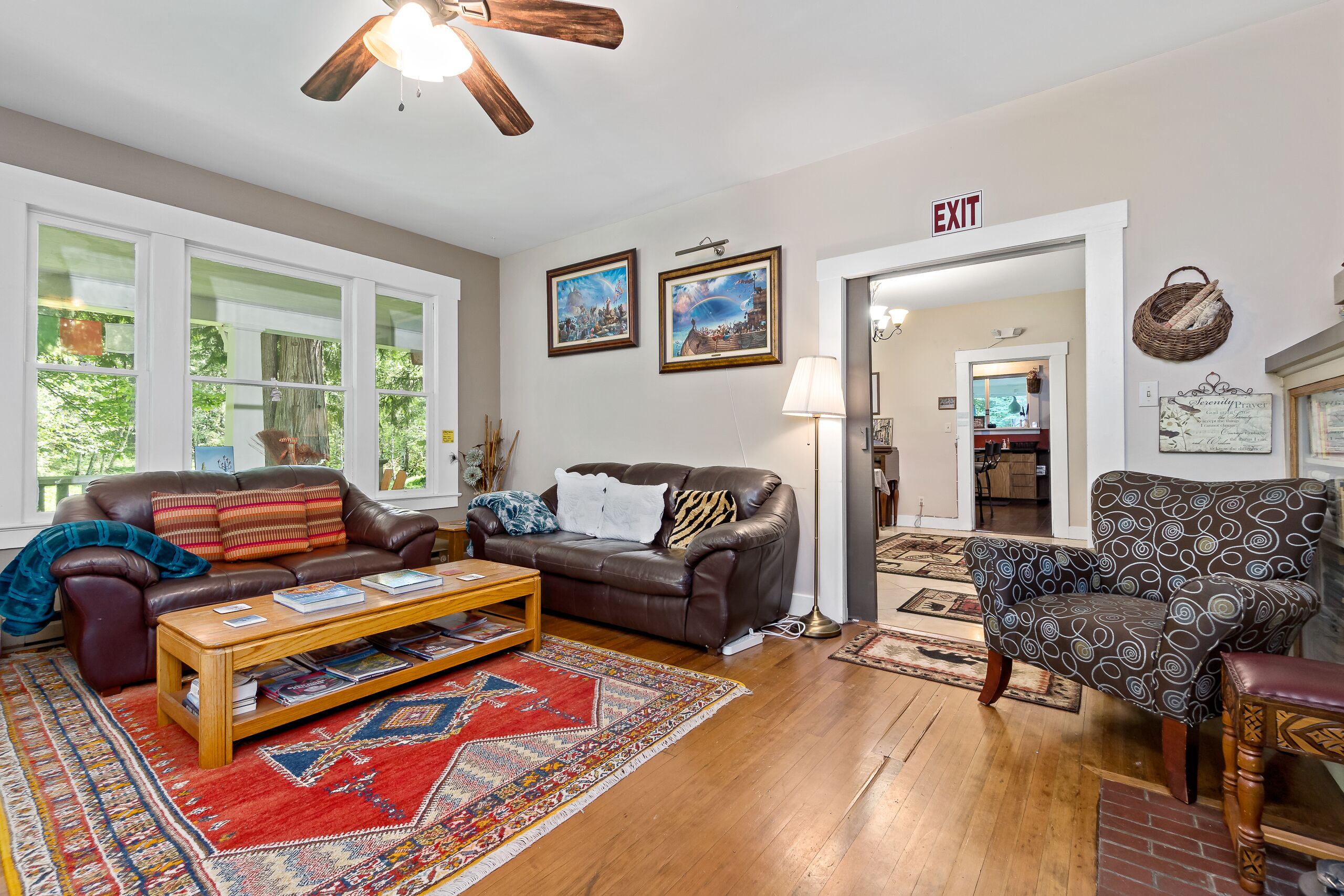 A living room with a brown leather sofa, a patterned armchair, a wooden coffee table, and a red and blue rug.