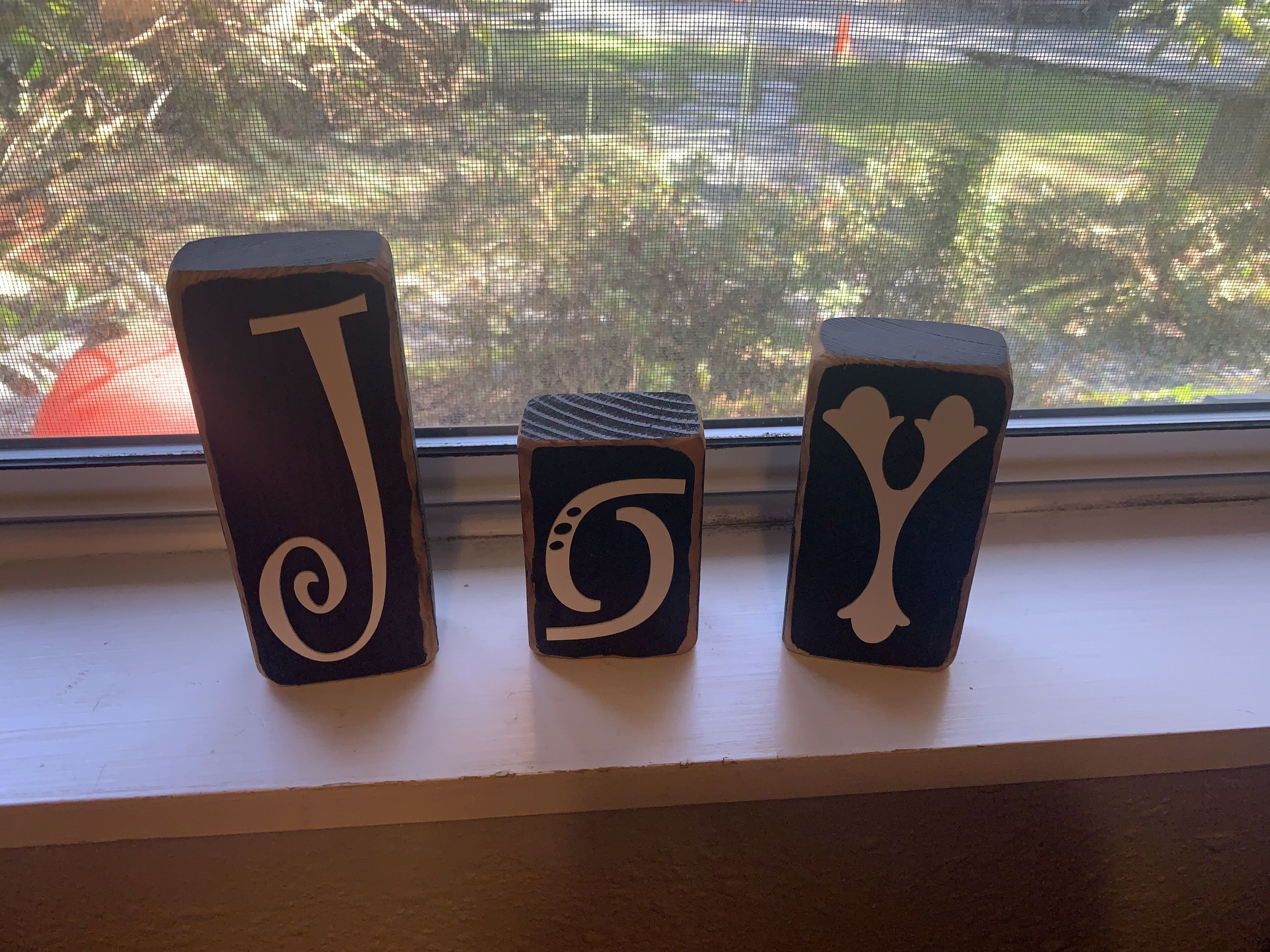Three wooden blocks with symbols on a windowsill.