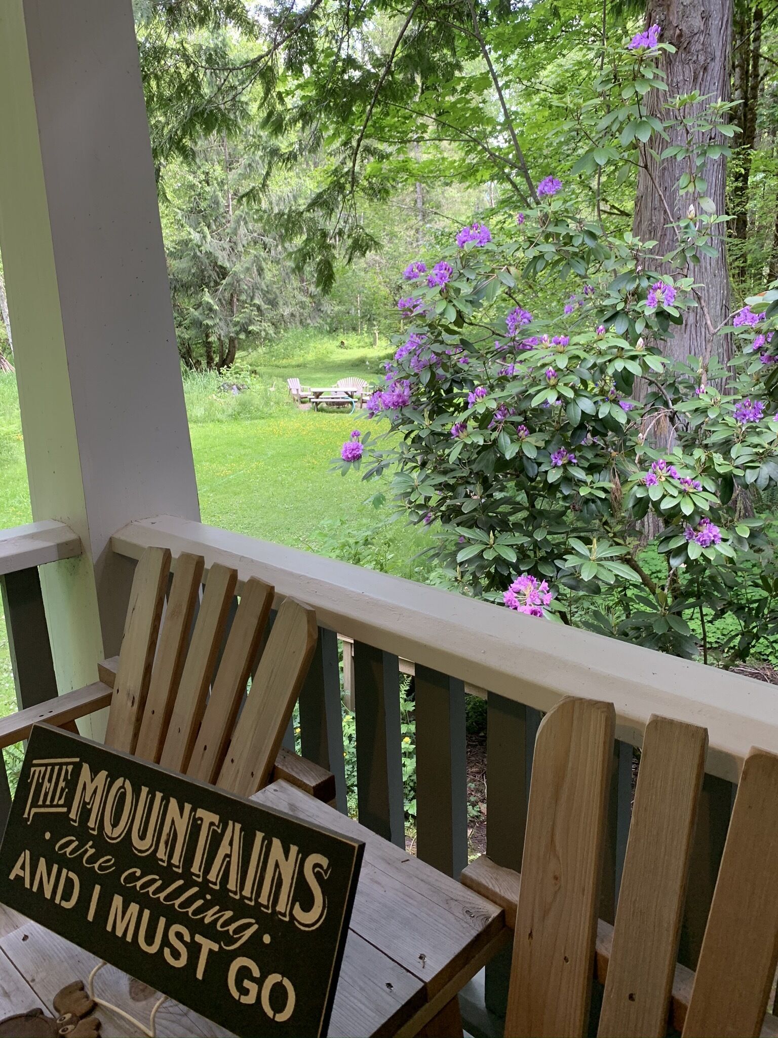 A wooden deck with a chair and a sign that reads "The Mountains are calling and I must go."