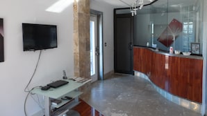 Un intérieur moderne avec un comptoir d’accueil incurvé, un téléviseur à écran plat fixé au mur et une cloison en verre.