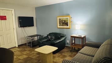 A living room with a sofa, a coffee table, a television, and a framed picture on the wall.