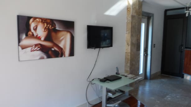 Un intérieur moderne avec une colonne en marbre, un téléviseur fixé au mur et un bureau avec un ordinateur.