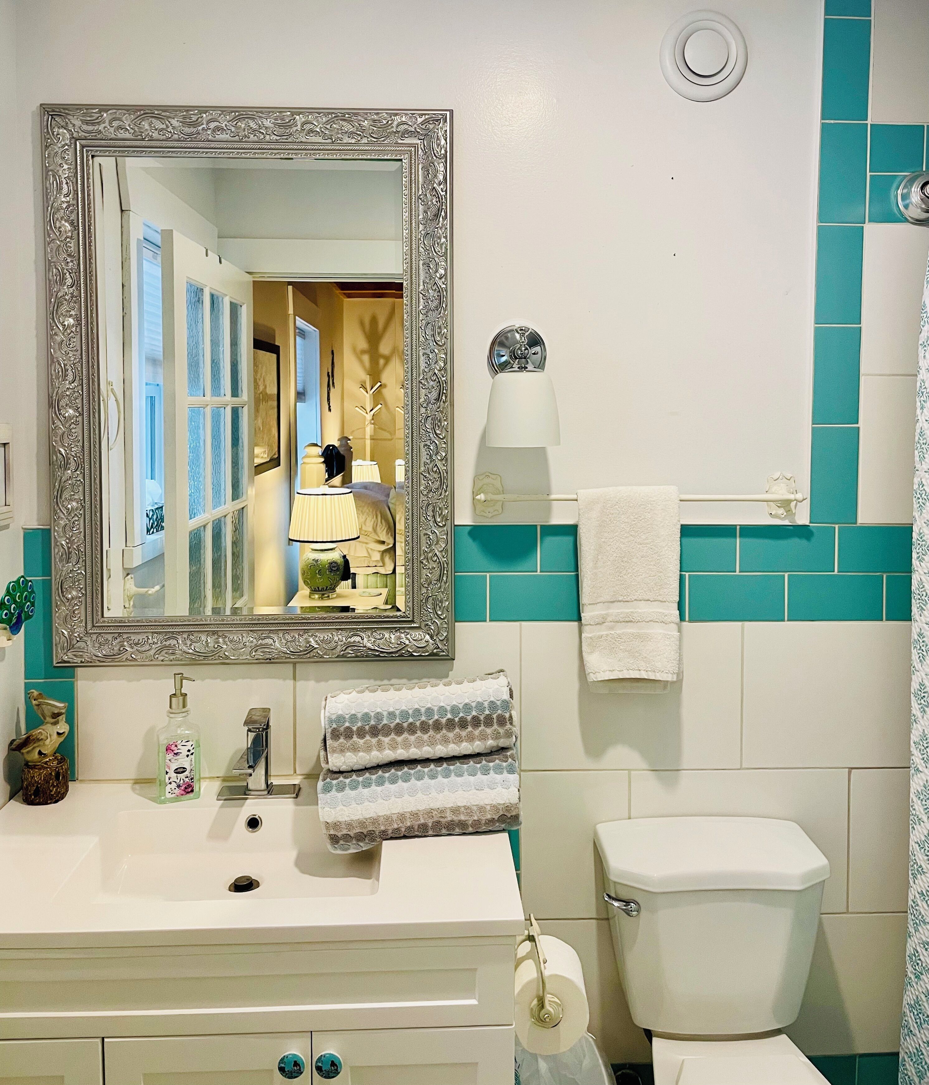 A bathroom with a white sink, a mirror with an ornate frame, a toilet, and a towel rack.