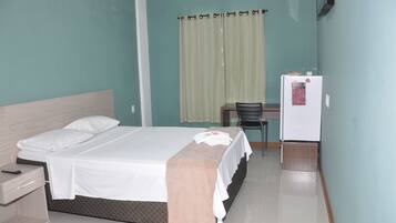 Une chambre d’hôtel équipée d’un lit, d’un bureau, d’une chaise et d’un réfrigérateur.